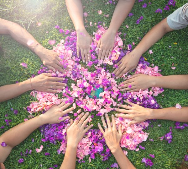 Women's circle Many hands touch each other on a bed of flowers
